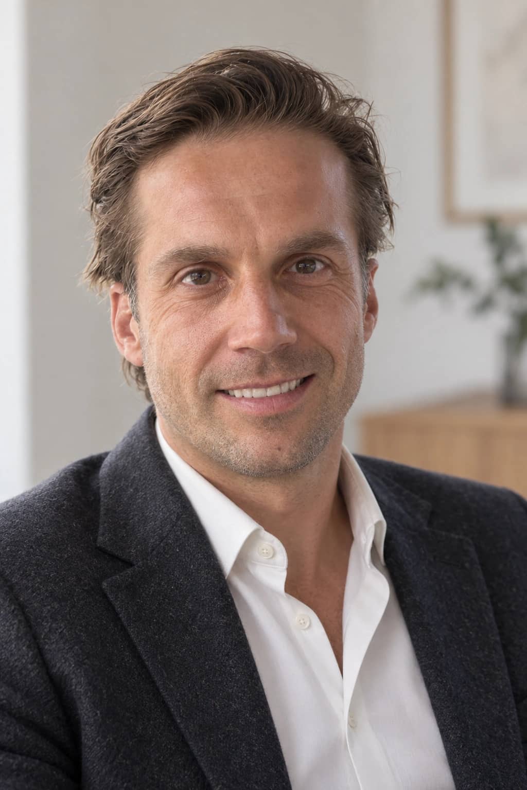 AI-generated close editorial portrait of Mathieu smiling in a charcoal jacket and ivory shirt in natural studio light.