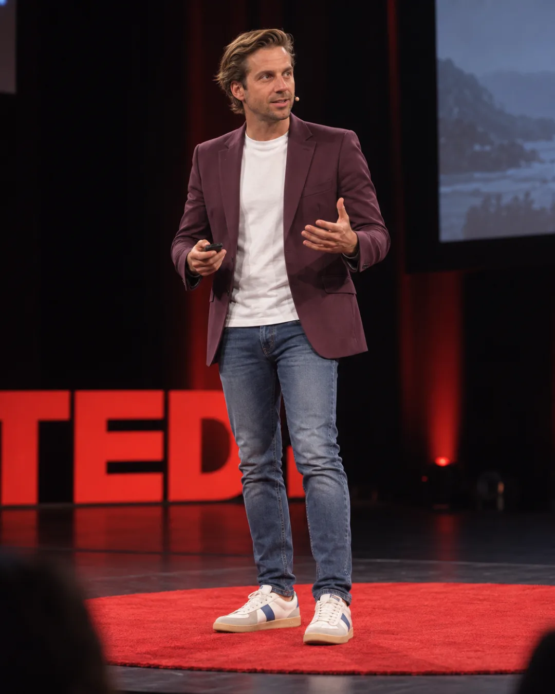 The founder on a conference stage, explaining something with both hands