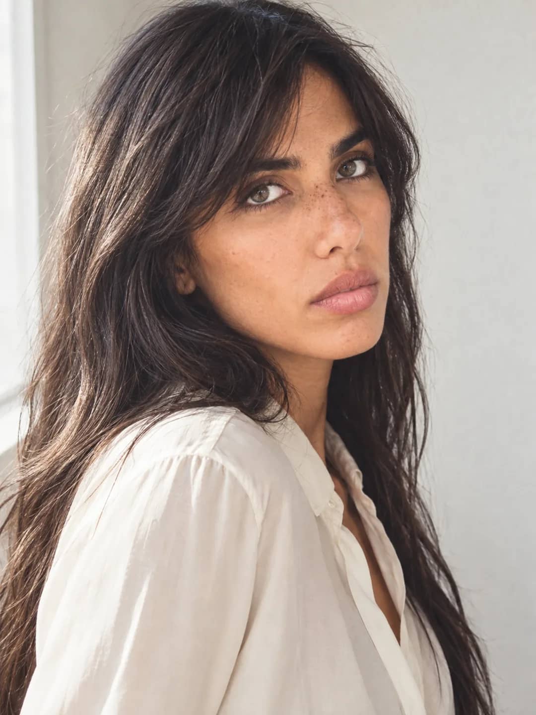 AI-generated close portrait of Danielle in a cream shirt in soft daylight